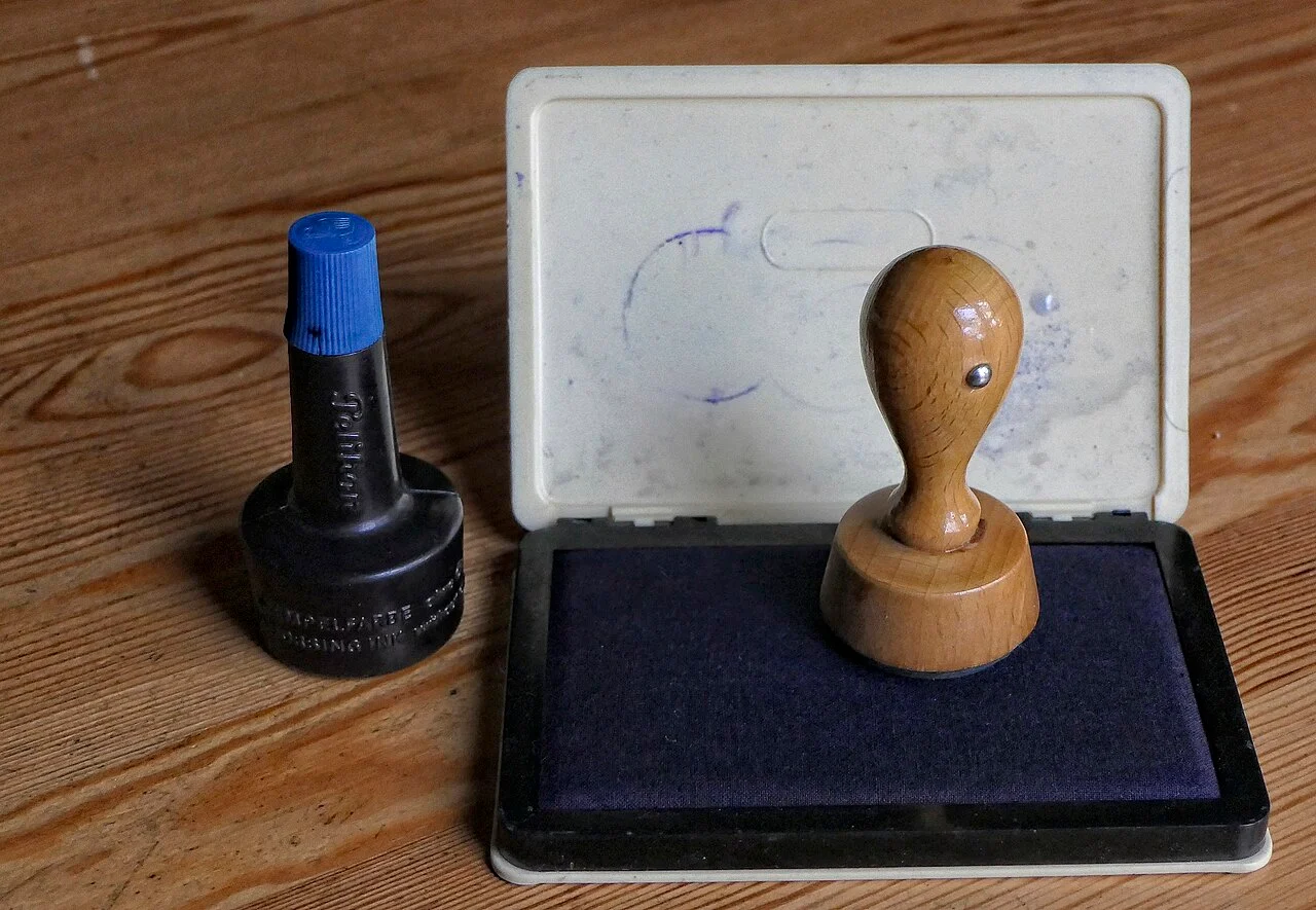 A rubber stamp, ink pad and bottle of stamp ink on a table.
