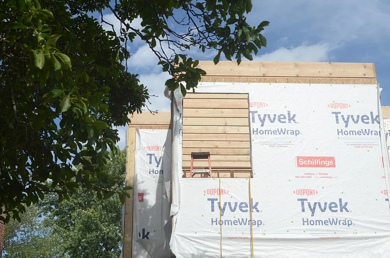 Timber framing of a house under construction, with materials around the building.