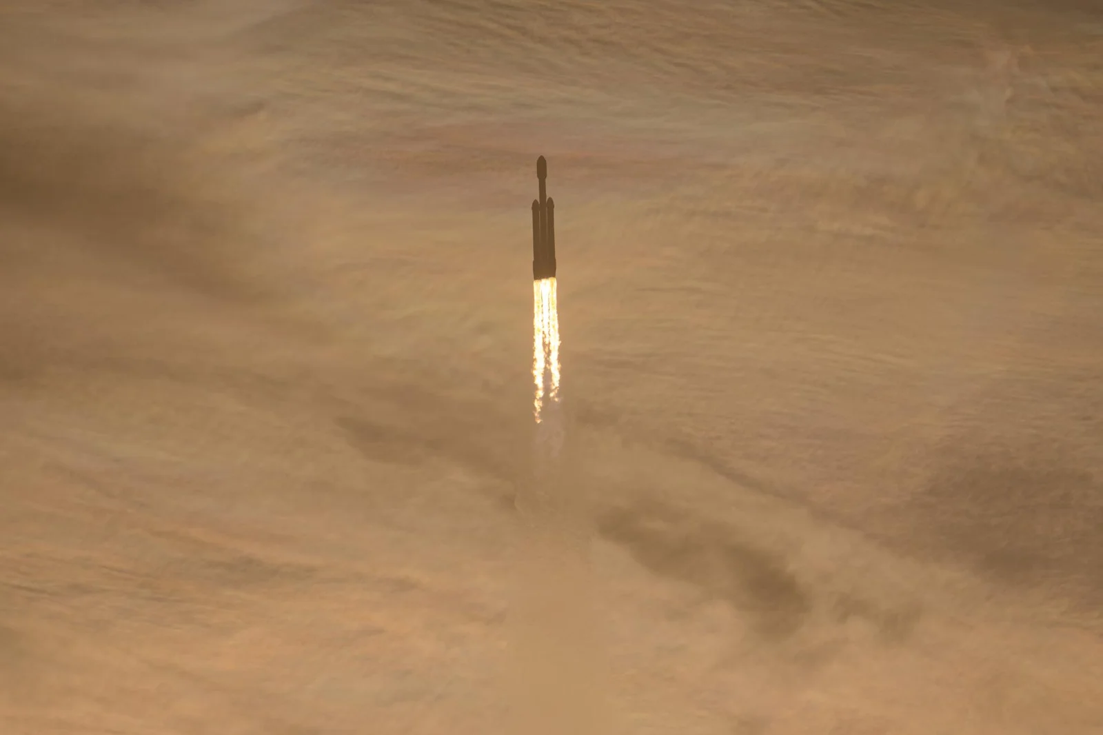A SpaceX Falcon Heavy carrying NASA's Nancy Grace Roman Space Telescope climbs through golden clouds after launch
