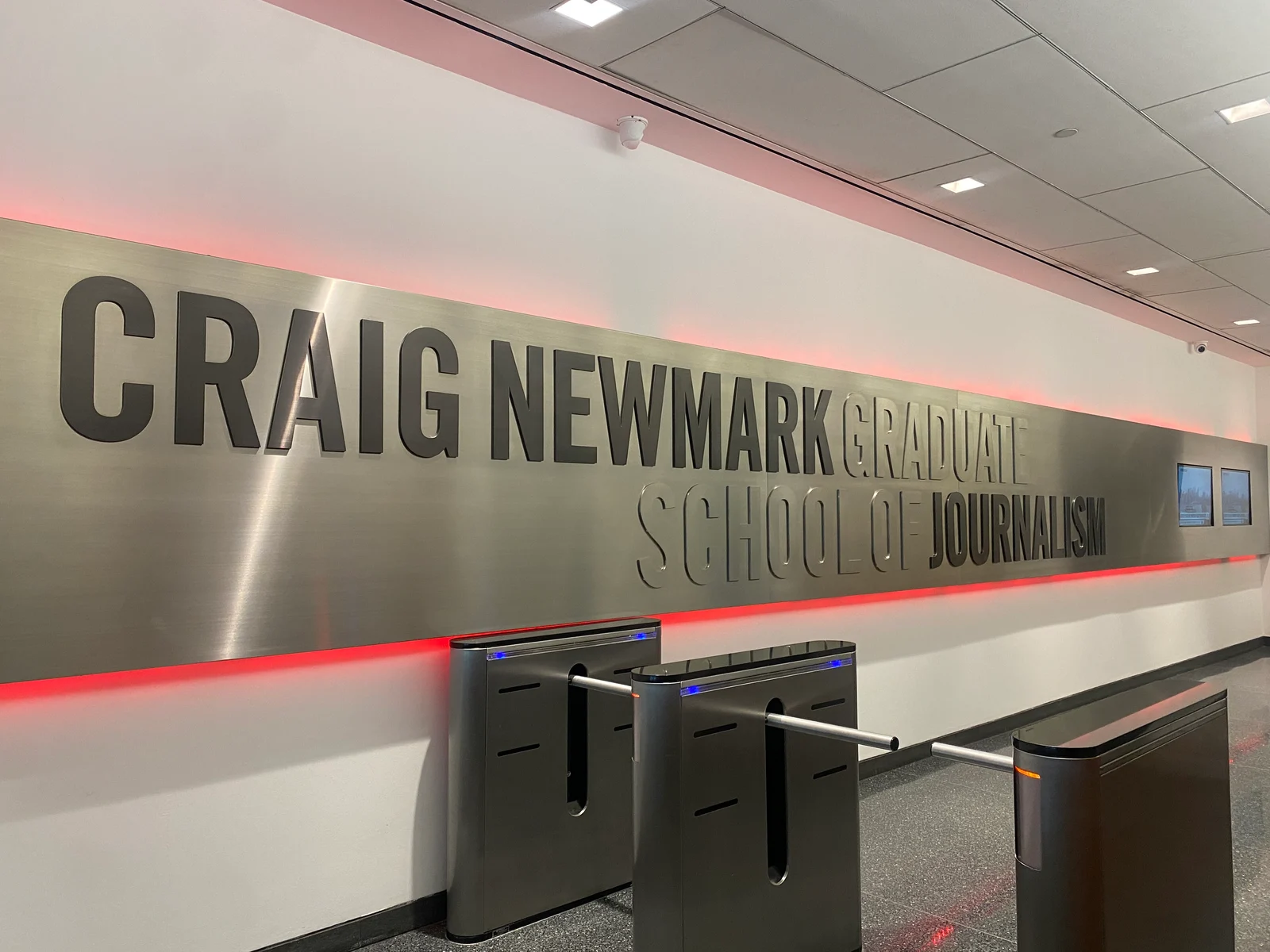 Interior entrance to the Craig Newmark Graduate School of Journalism, with its name displayed above security turnstiles