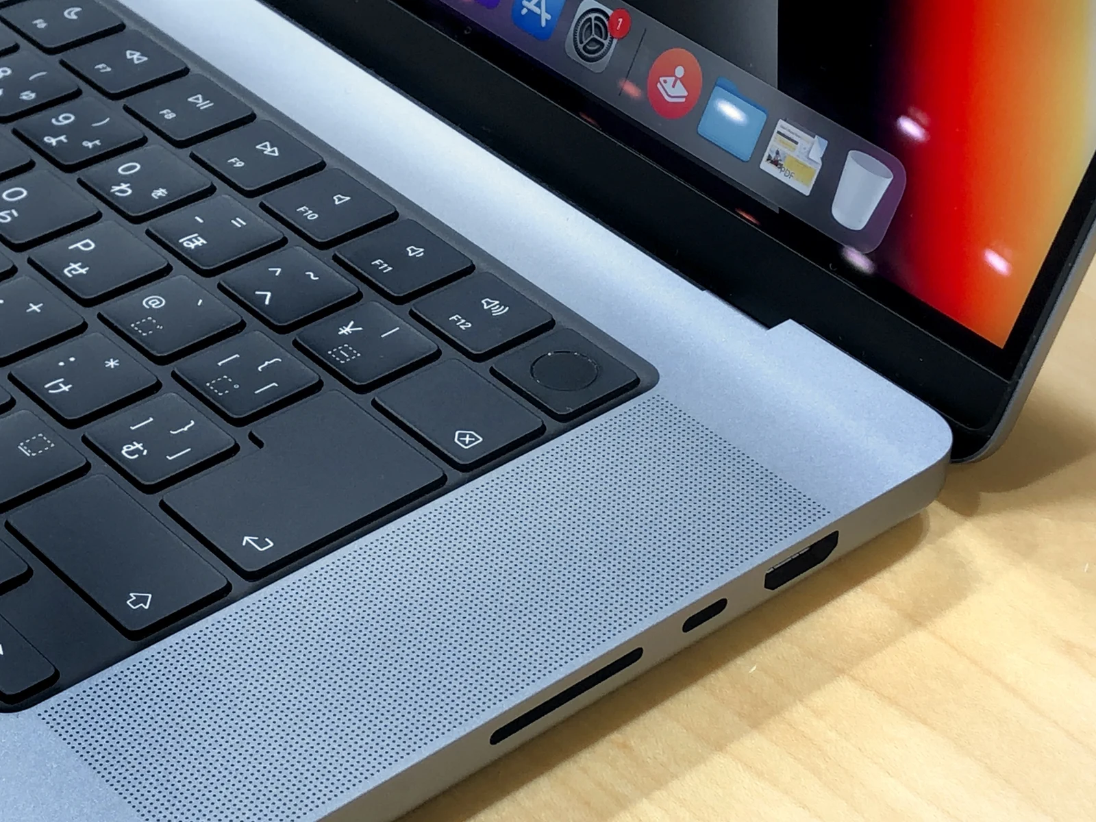 Close-up photograph of the side of a 2021 16-inch MacBook Pro showing the Touch ID button and SD card slot, representative of the Apple Silicon laptops targeted by the new GGUF support.